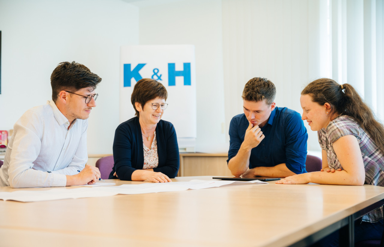 Menschen an einem Tisch, über einen Plan gebeugt.